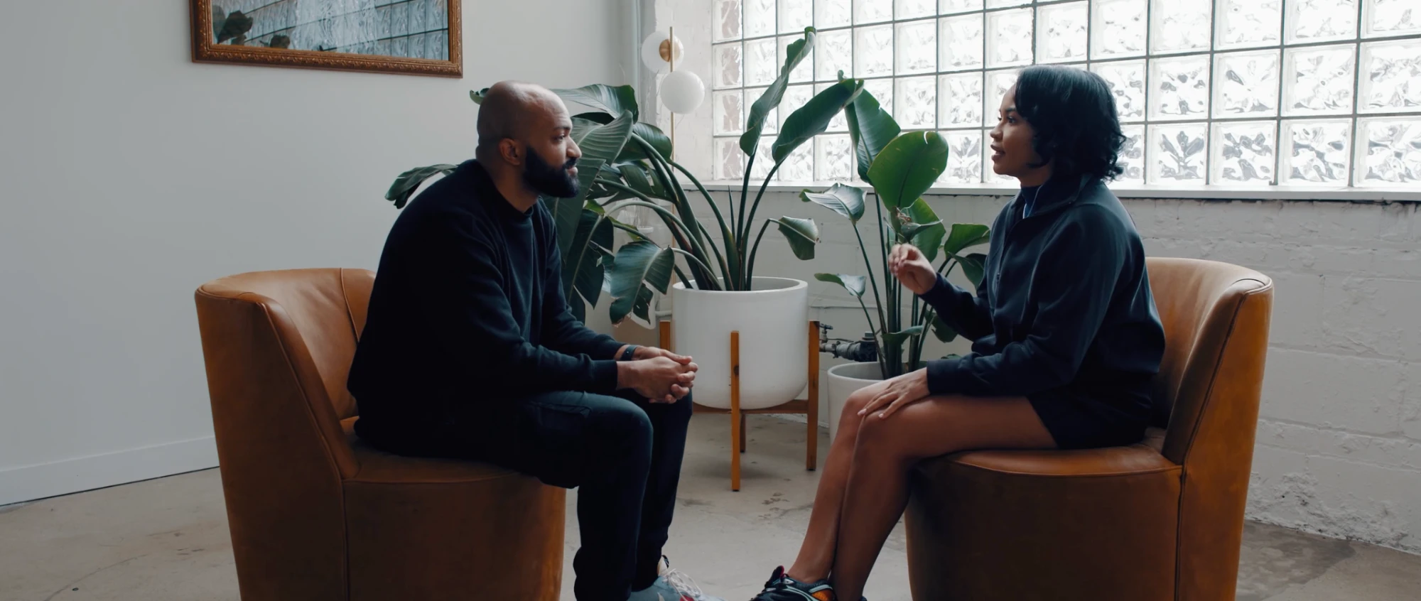 Two people seated in leather chairs during an interview in a bright studio
